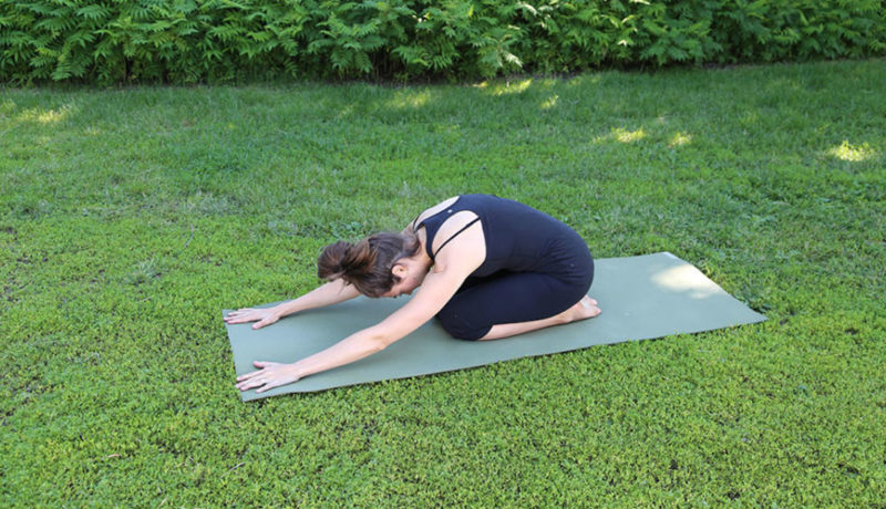 femme dans un parc faisant la position du coquillage en yoga