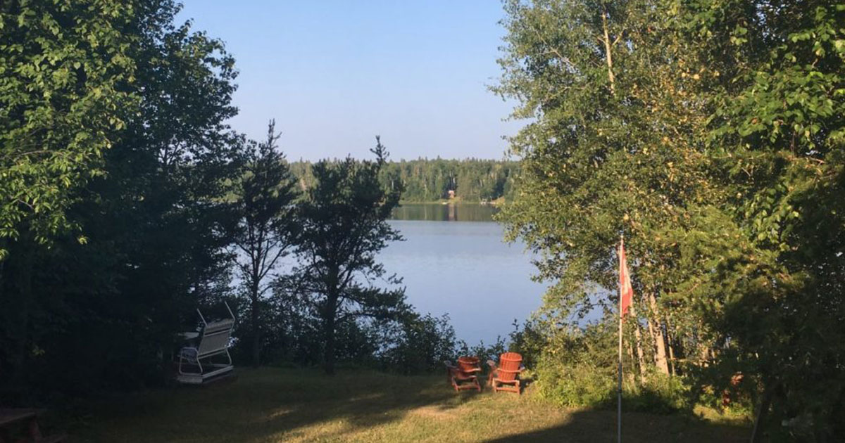 Chaises rouge dans une cours faisant face à un lac en forêt