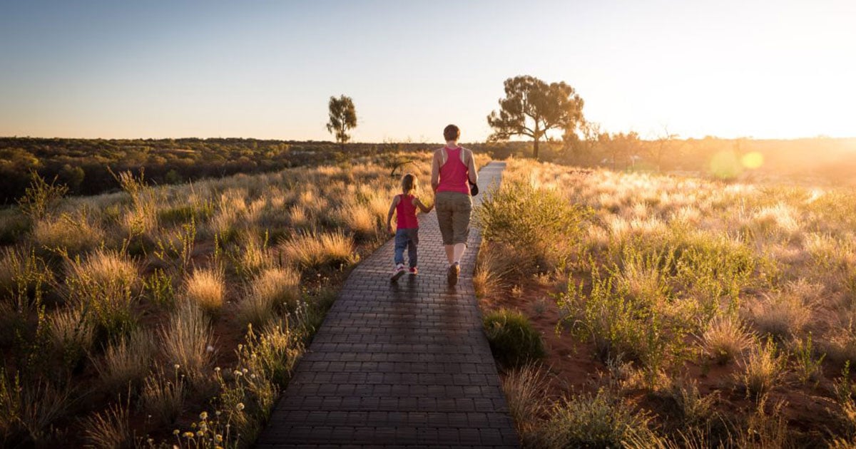 Femme et enfants marchant sur un sentier au coucher de soleil