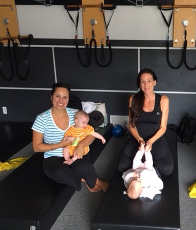 2 moms sitting on mat with babies